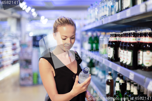 Image of Woman choosing mineral water in grocery store.