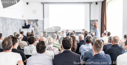 Image of I have a question. Group of business people sitting in conference hall. Businessman raising his arm. Conference and Presentation. Business and Entrepreneurship