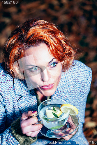 Image of portrait of a smiling young woman drinking glass