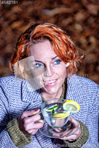 Image of portrait of a smiling young woman drinking glass