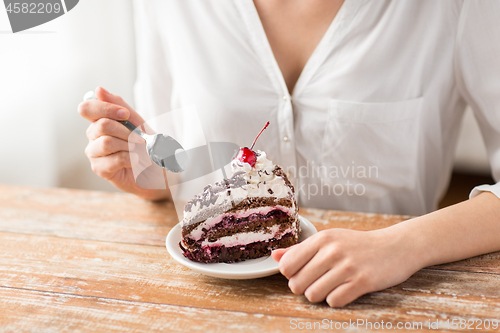 Image of woman eating piece of layer cake with cherry
