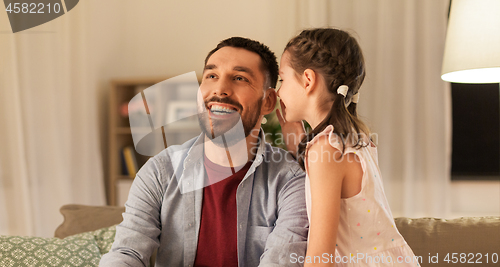 Image of happy daughter whispering secret to father at home