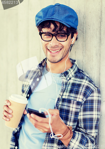 Image of man with earphones and smartphone drinking coffee