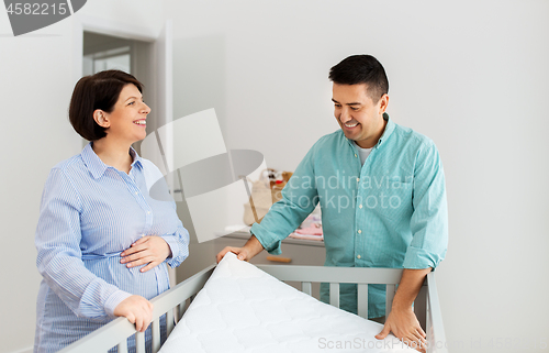 Image of family couple arranging baby bed with mattress