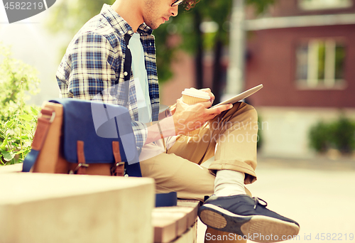 Image of man with tablet pc and coffee on city street bench