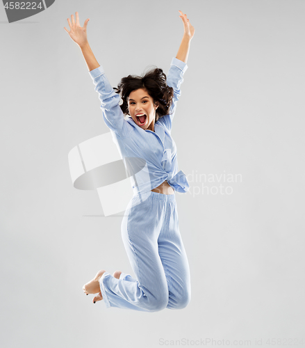 Image of happy woman in blue pajama jumping high