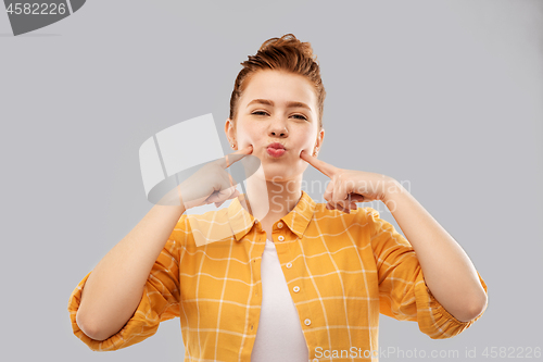 Image of smiling red haired teenage girl blowing her cheeks