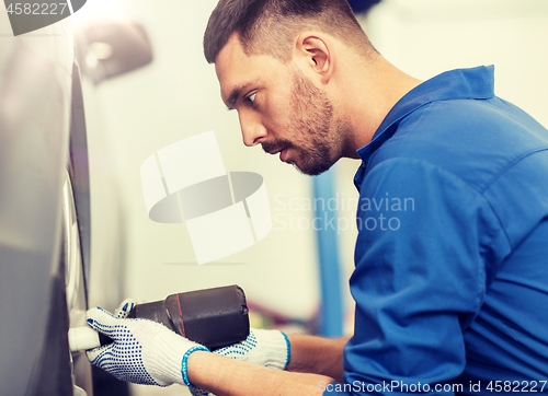 Image of mechanic with screwdriver changing car tire