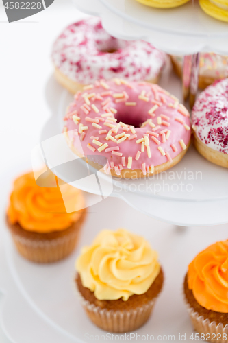 Image of close up of glazed donuts and cupcakes on stand