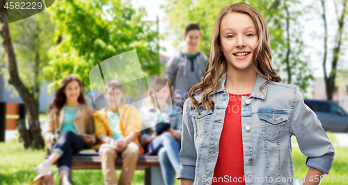 Image of smiling teenage girl in denim jacket over friends