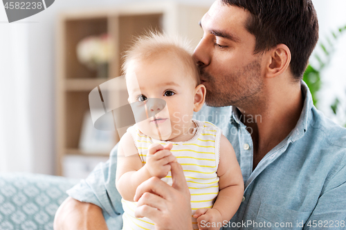 Image of father kissing little baby daughter