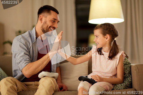 Image of father and daughter playing video game at home