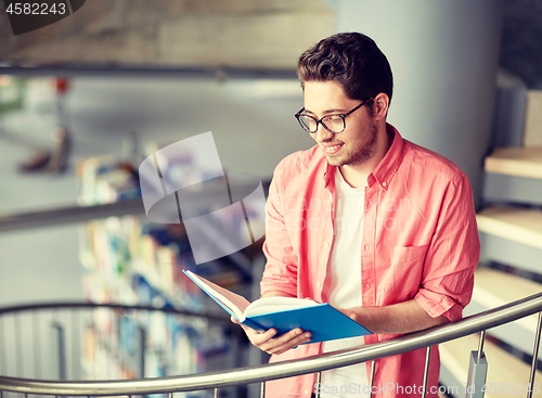 Image of student boy or young man reading book at library