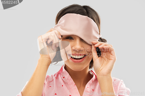 Image of happy young woman peeking from under sleeping mask