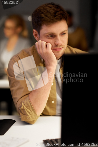 Image of tired or bored man on table at night office