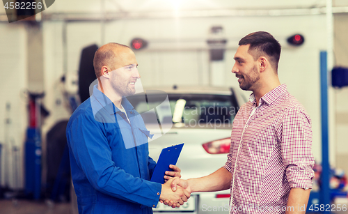 Image of auto mechanic and man shaking hands at car shop