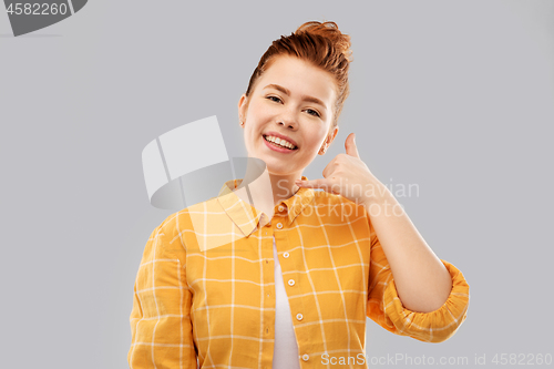 Image of redhead teenage girl making phone call gesture