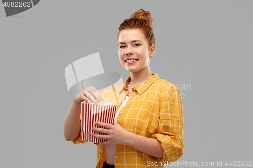 Image of smiling red haired teenage girl eating popcorn