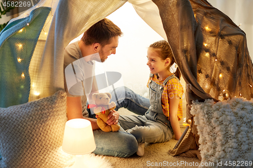 Image of happy family playing with toy in kids tent at home