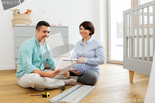 Image of family couple with user manual assembling baby bed