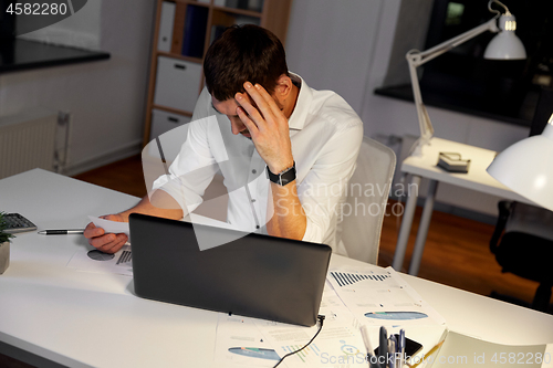 Image of businessman with papers working at night office