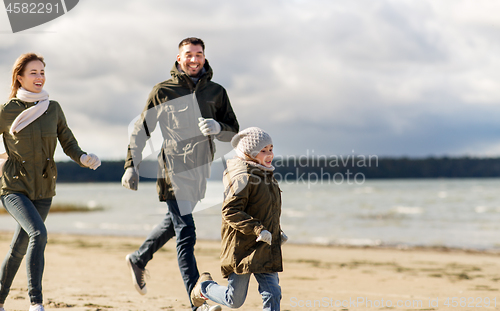 Image of happy family running along autumn beach