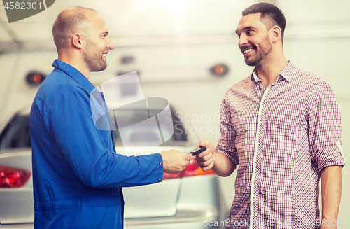 Image of auto mechanic giving key to man at car shop