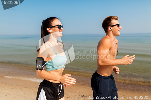 Image of couple with phones and arm bands running on beach