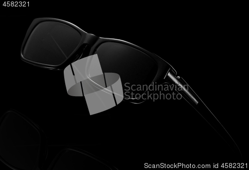 Image of Black sunglasses on a dark background.