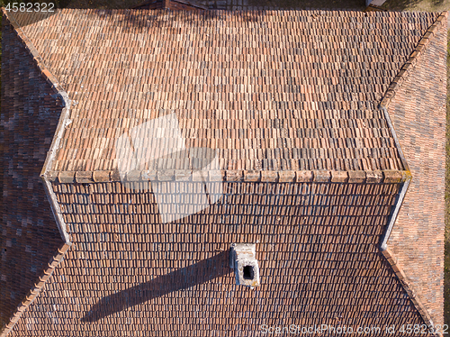 Image of Top view of tile roof with chimney and shadows.