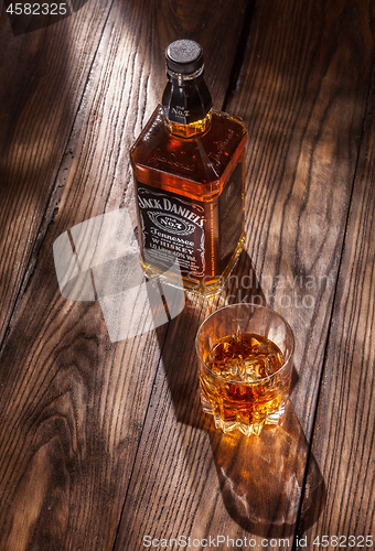 Image of UKRAINE, KYIV-MARCH 11, 2015. Bottle of Jack Daniel\'s Tennessee whiskey with glass of drink on a wooden table.