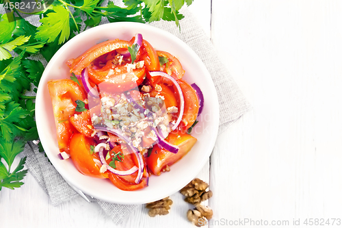 Image of Salad with tomato and walnut in plate on board top