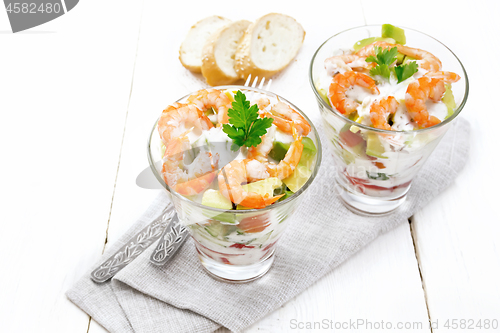 Image of Salad with shrimp and avocado in two glasses on white board