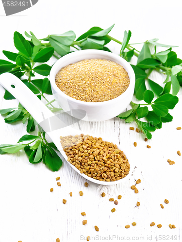 Image of Fenugreek in spoon and bowl with leaves on white wooden board