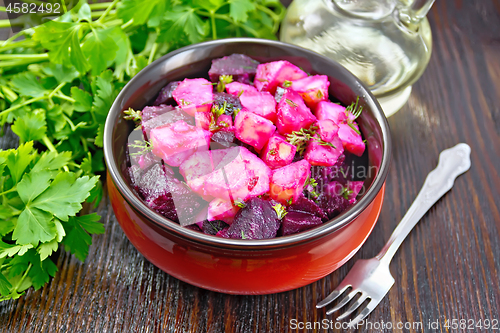 Image of Salad of beets and potatoes with oil in bowl on table
