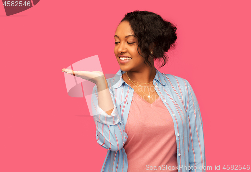 Image of happy african woman holding something on hand