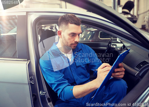 Image of auto mechanic man with clipboard at car workshop