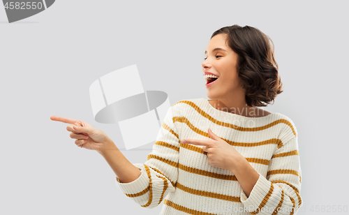 Image of happy smiling woman pointing fingers to something