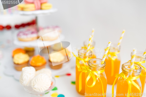 Image of orange juice in glass bottles with paper straws