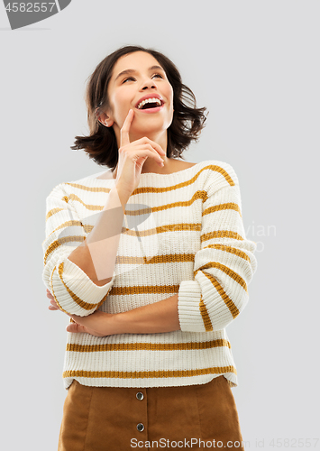 Image of happy woman in striped pullover looking up