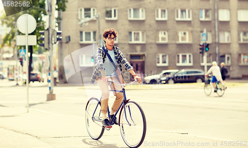 Image of young hipster man with bag riding fixed gear bike