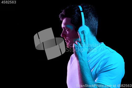 Image of man in headphones over neon lights of night club