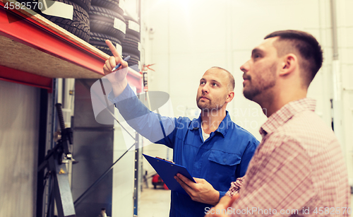 Image of auto mechanic with clipboard and man at car shop