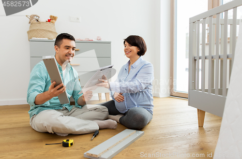 Image of family couple with user manual assembling baby bed