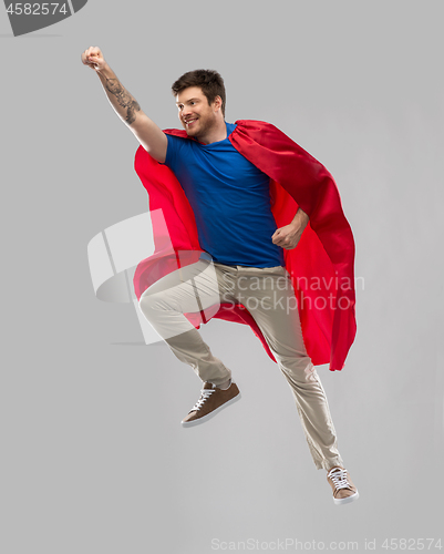 Image of man in red superhero cape flying in air