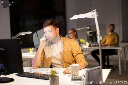 Image of man calling on smartphone at night office