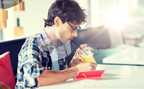 Image of man with notebook and juice writing at cafe