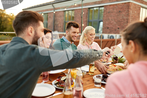 Image of friends eating burgers at dinner party on rooftop