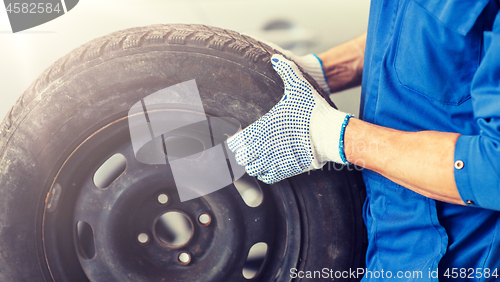 Image of mechanic with wheel tire at car workshop