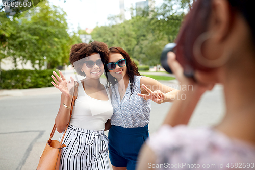 Image of woman photographing her friends in summer park